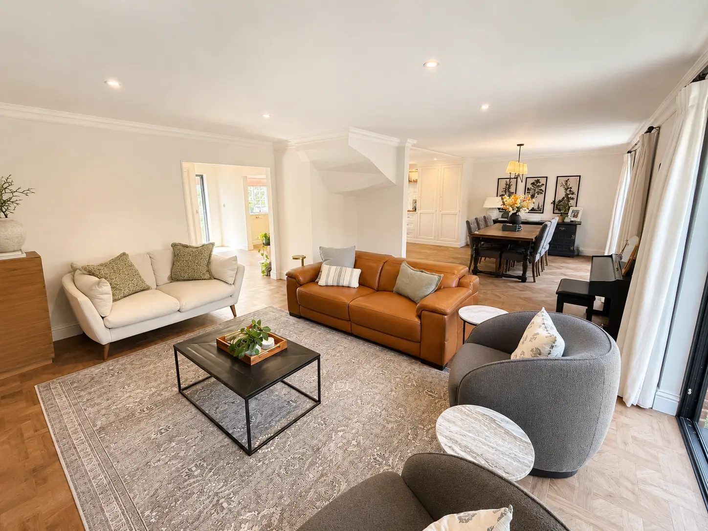 Open-plan sitting room with leather and linen sofas leading through to the dining area
