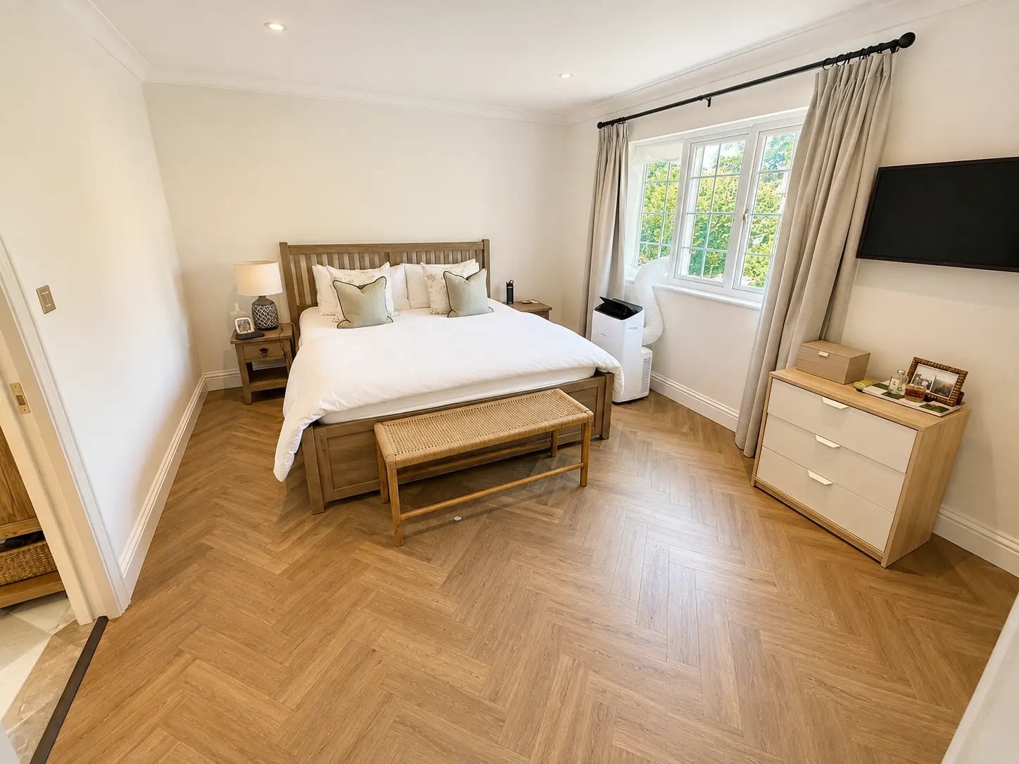 Main bedroom with a king bed, herringbone floor and wall-mounted television