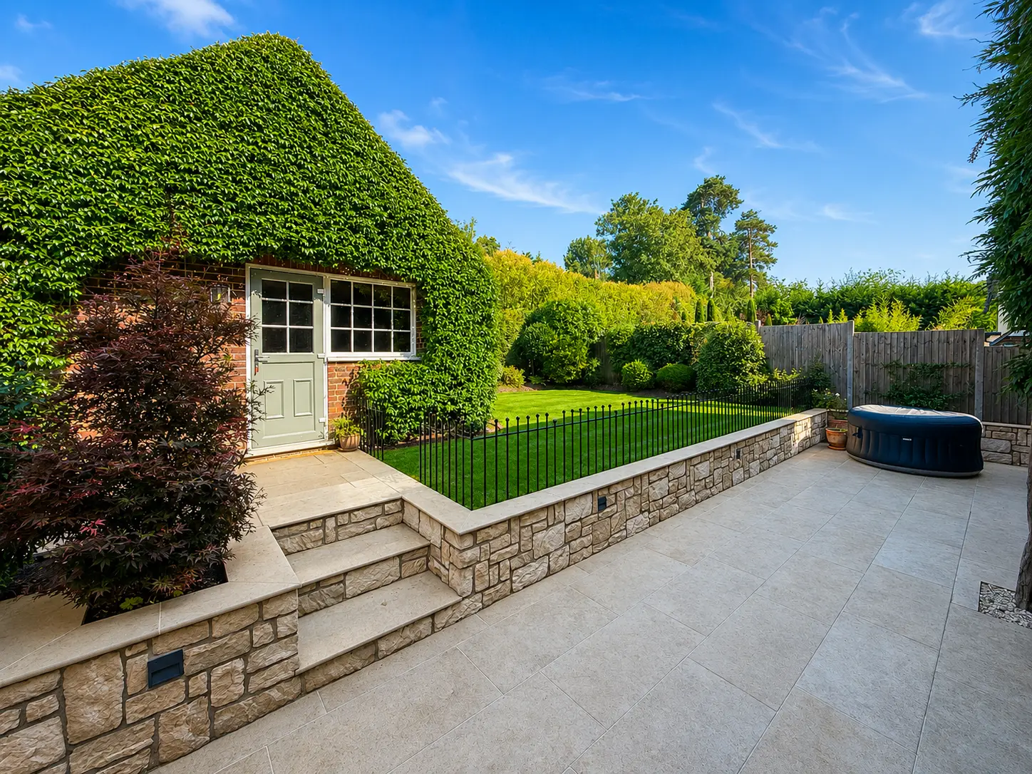Garden terrace with steps up to the lawn and an outbuilding